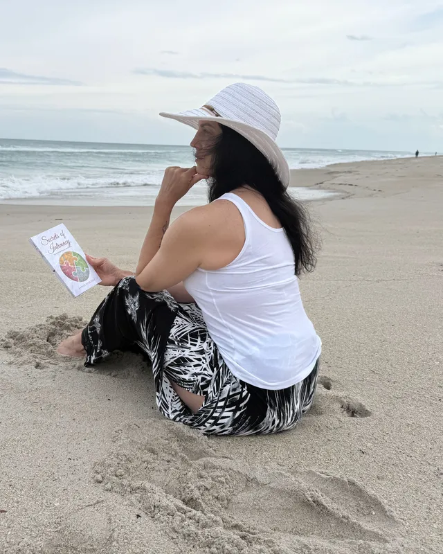A reader sitting on the sand with Seasons of Intimacy